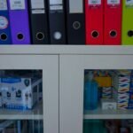 a glass door cabinet with a bunch of folders on top of it